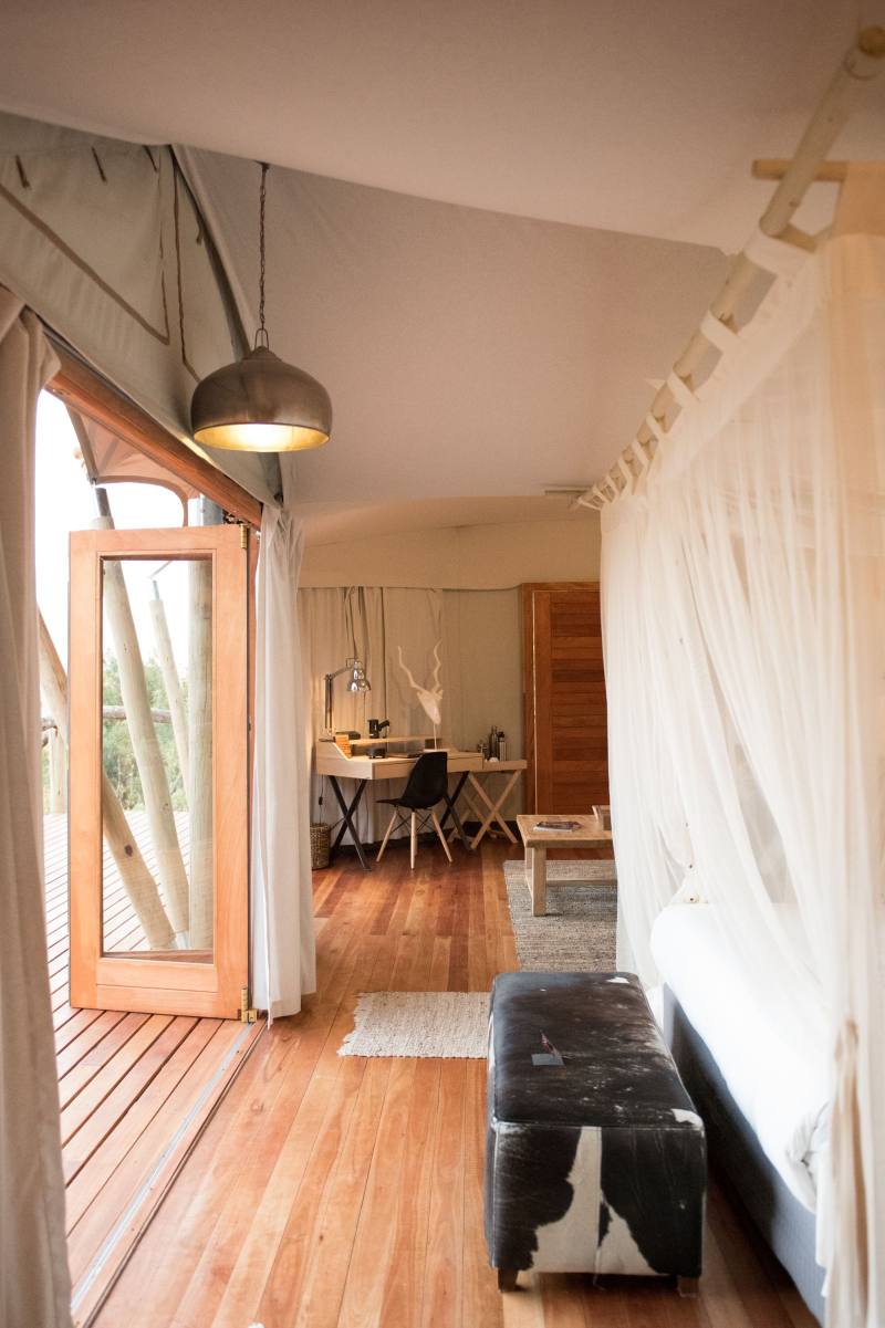 A bench beside white curtains at the doorway of a tent