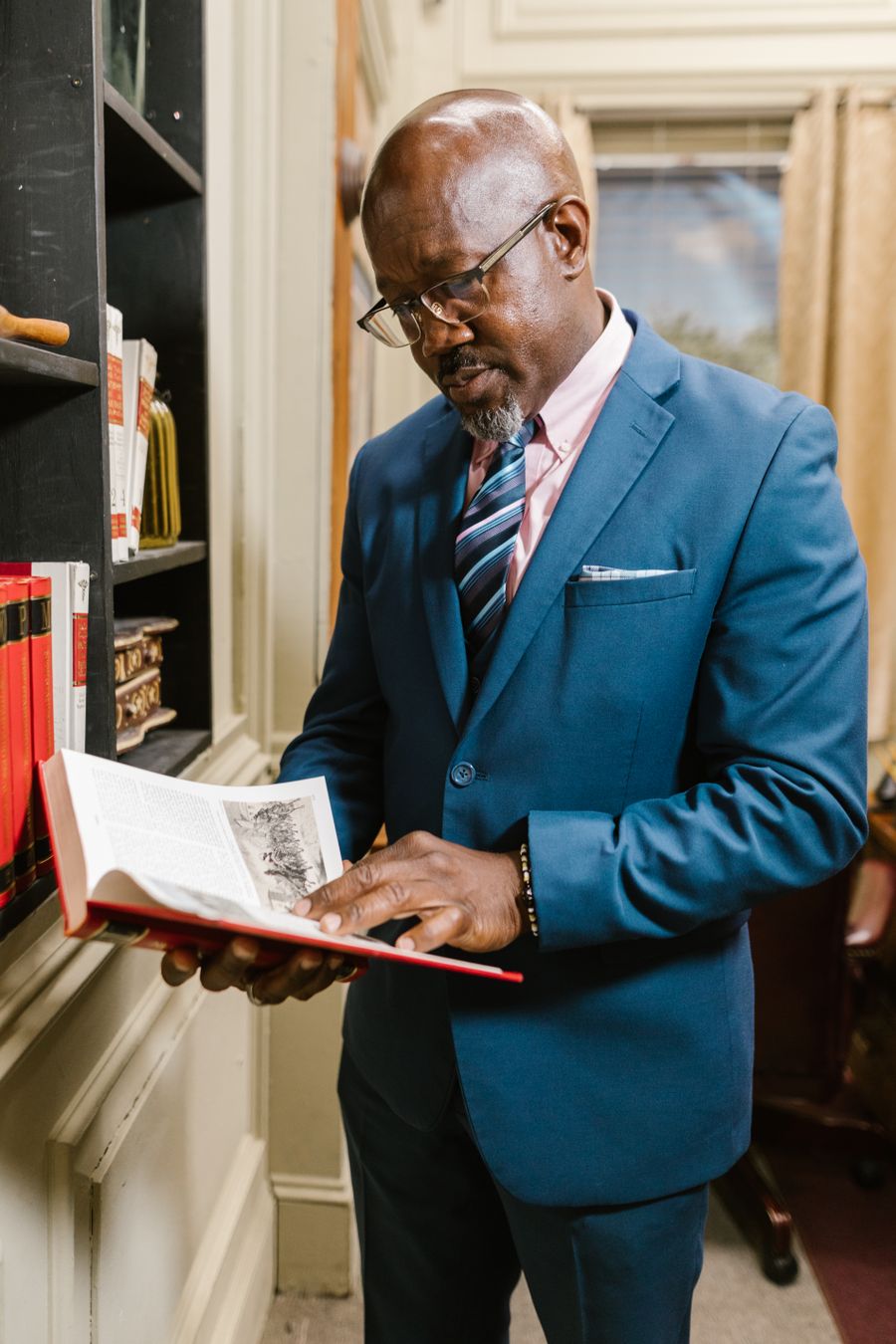Samuel Adeyemi, Senior Partner, in a blue suit holding a law book