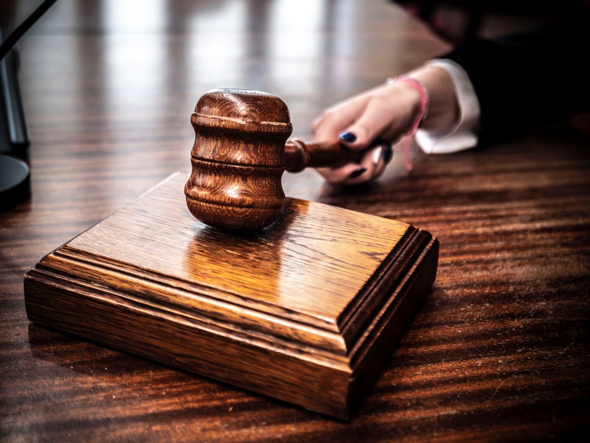 A wooden judge's gavel on a sound block on a polished wooden desk