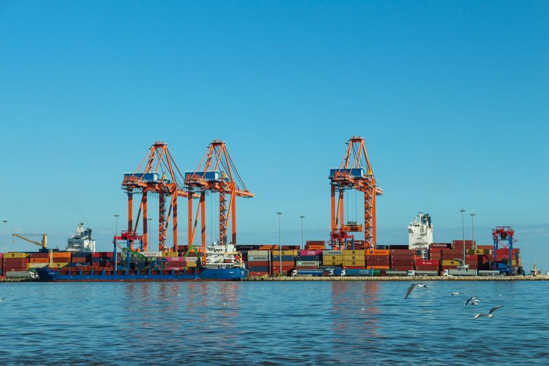 Container cranes across a calm harbour on a blue day