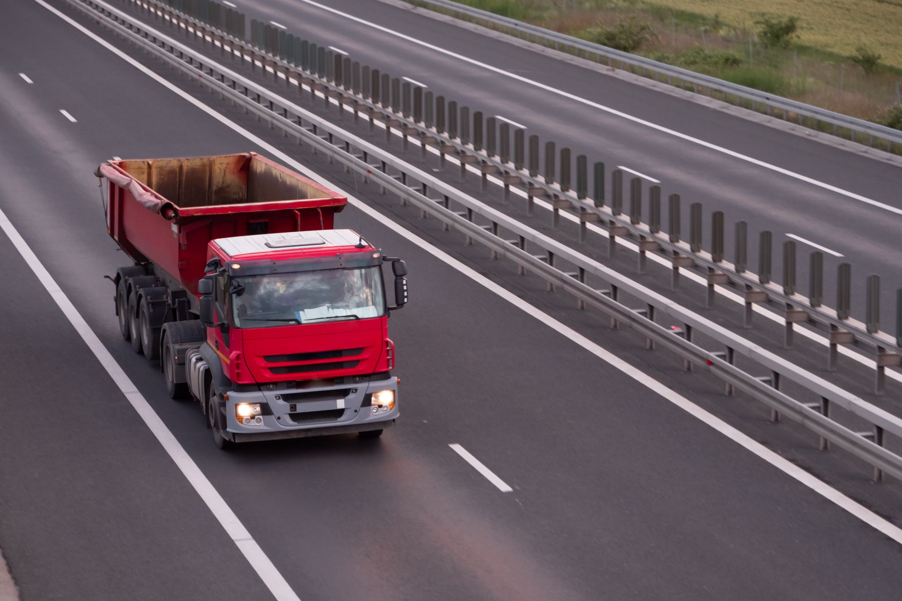 A red freight truck driving along a multi-lane highway