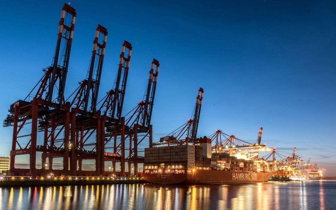 Container cranes at a seaport lit up at dusk