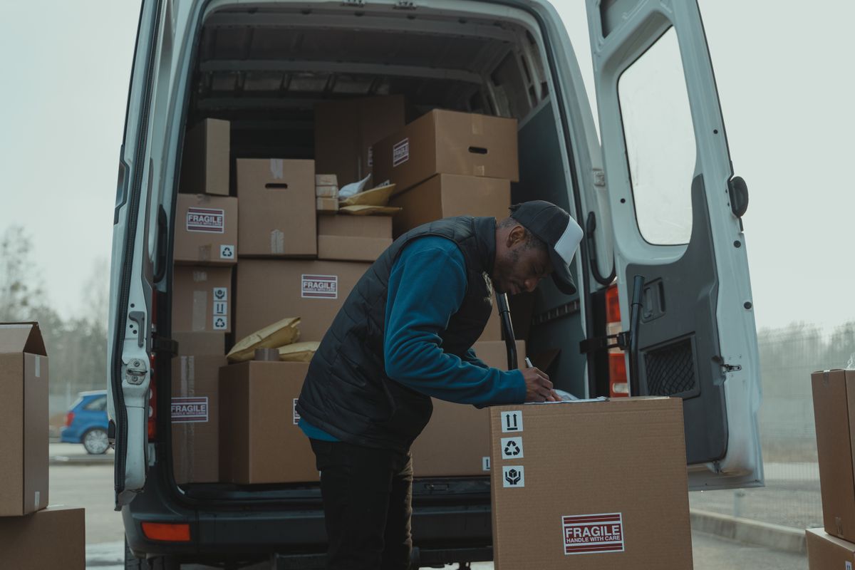 A delivery driver checking parcels in the open back of a white van
