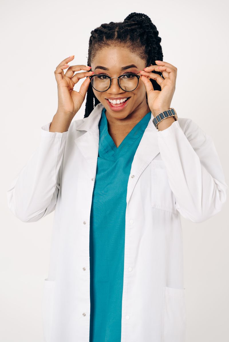 Dr Amina Okoye, General Practitioner, in a white coat and teal scrubs