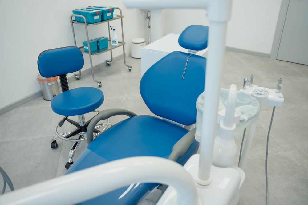 A modern dental treatment room with a blue chair and overhead light