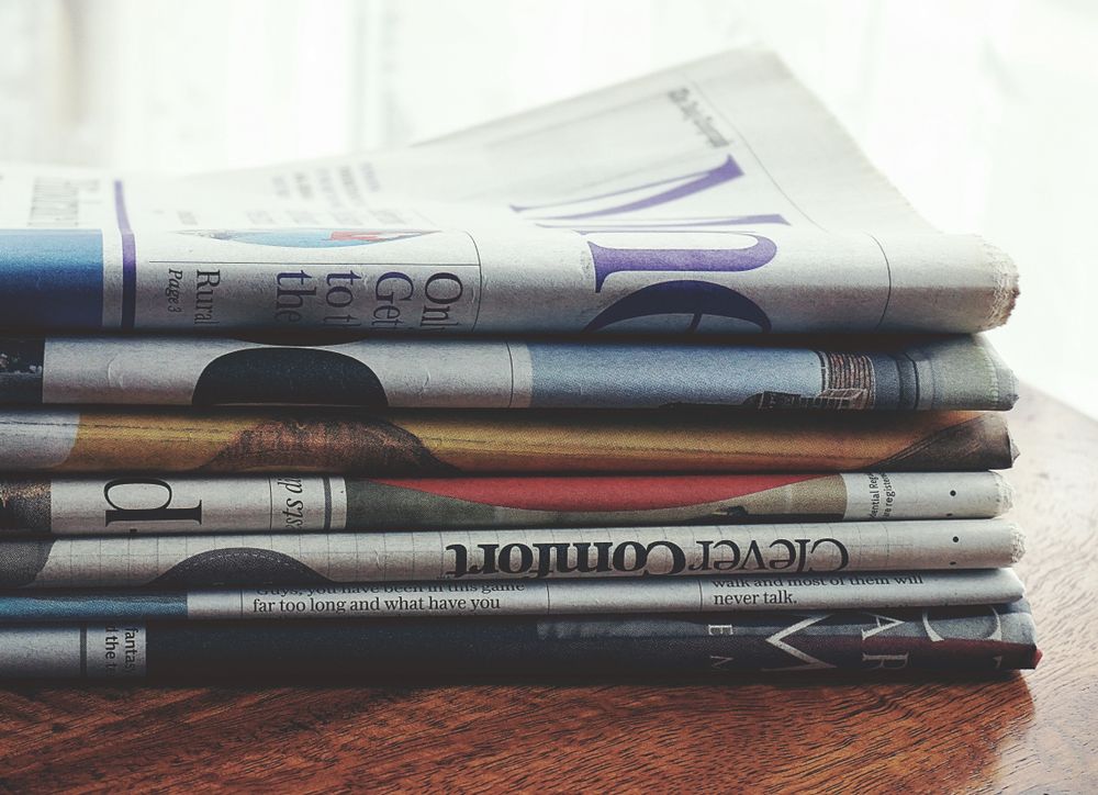A stack of folded newspapers on a wooden table