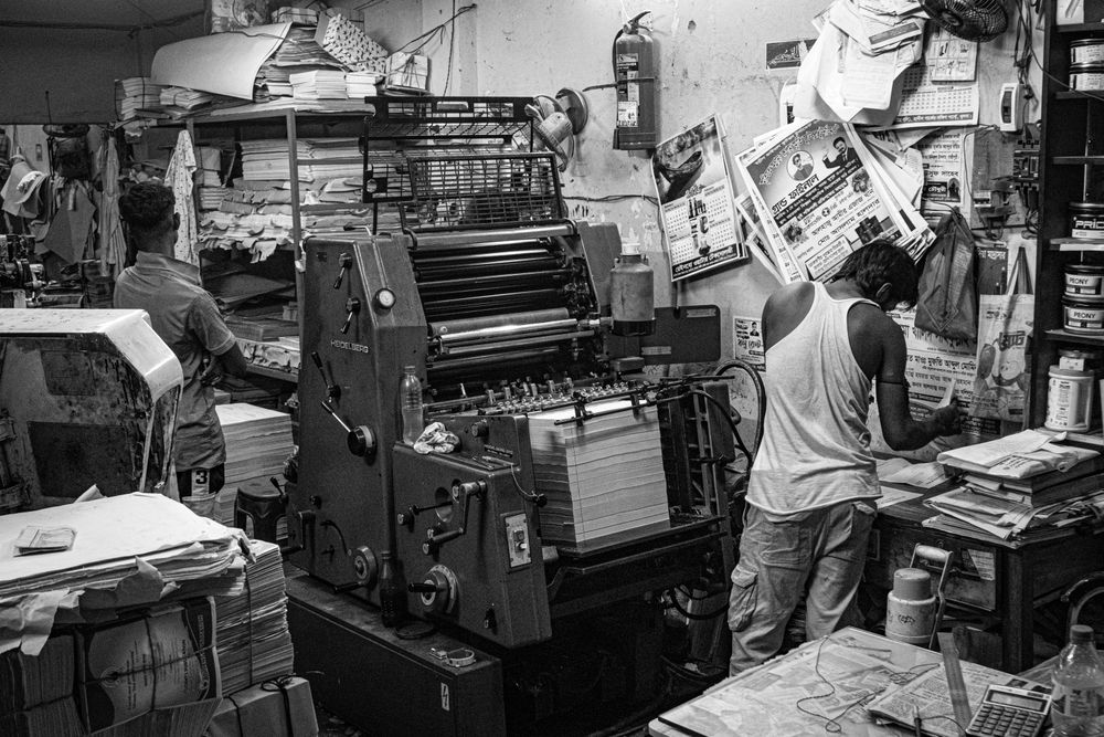 Workers operating a newspaper printing press