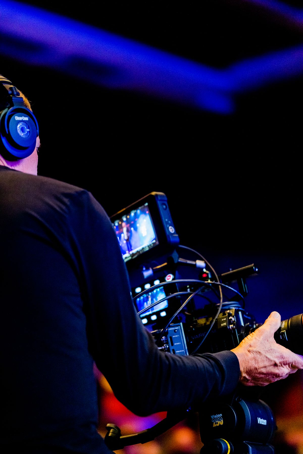 A camera operator wearing headphones at a broadcast desk