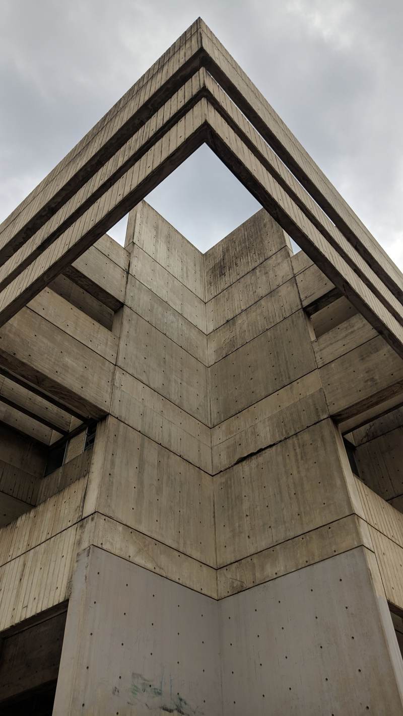 The angled concrete corner of a building seen from below