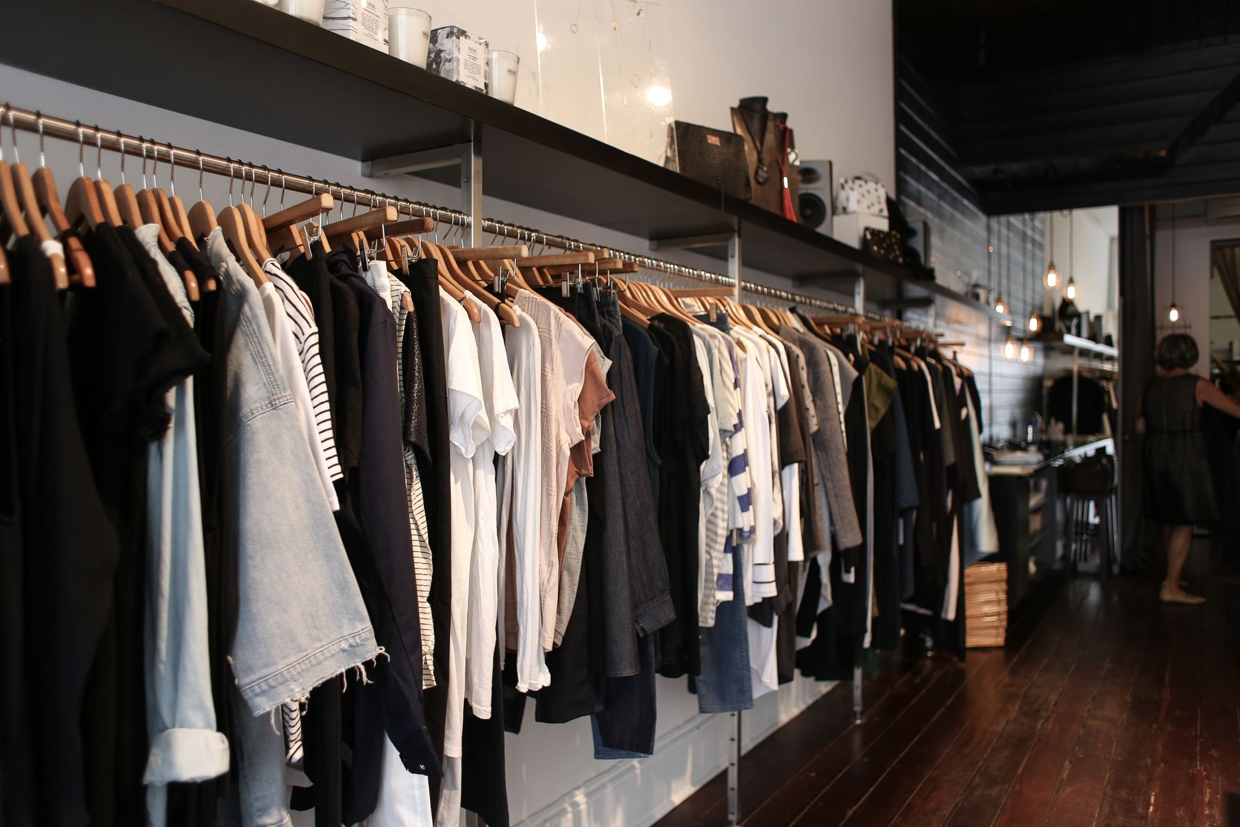 Clothing rails in a boutique with wooden hangers, denim and linen pieces and a timber floor