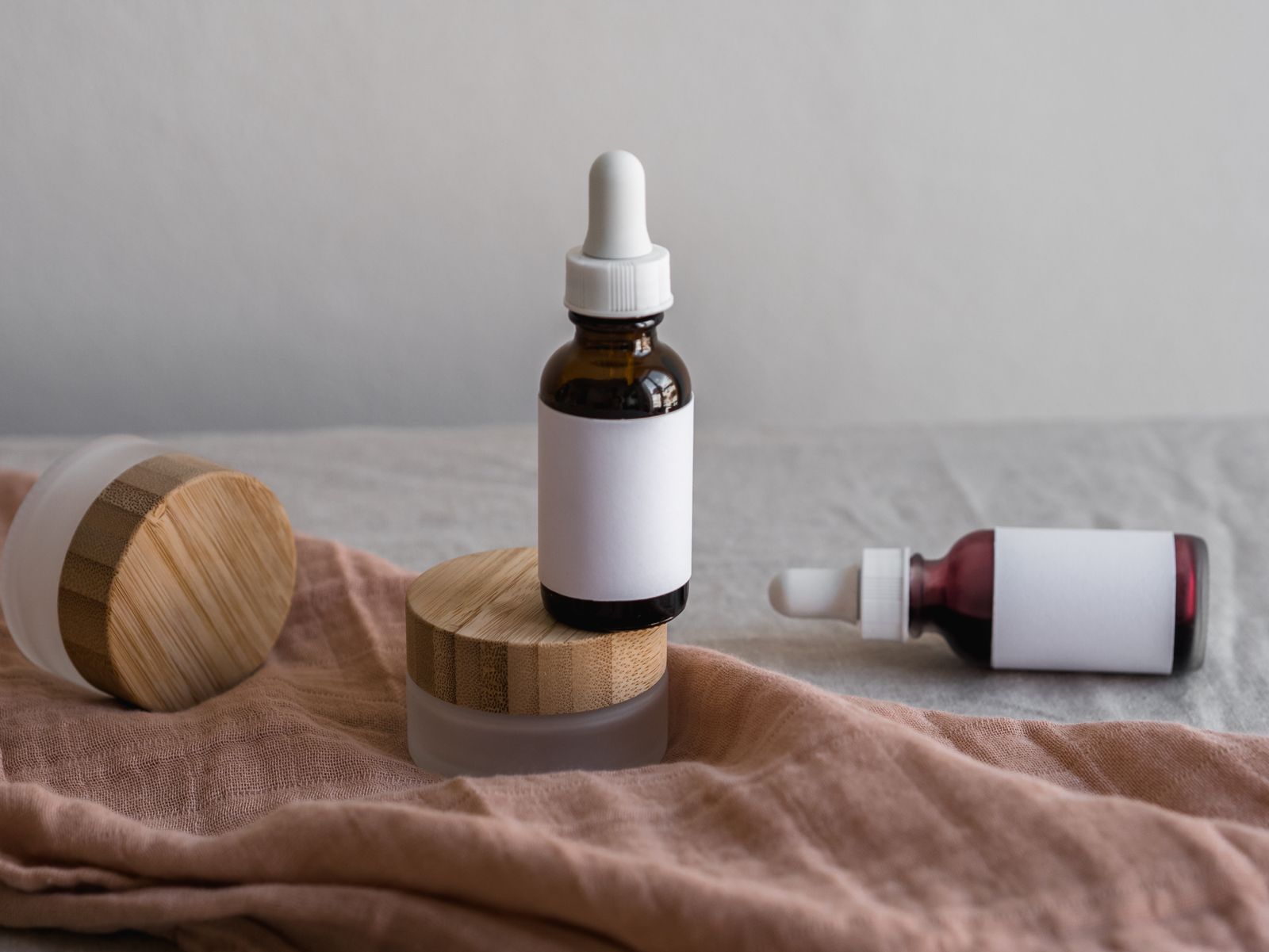 Amber dropper bottles and frosted jars on a blush linen cloth
