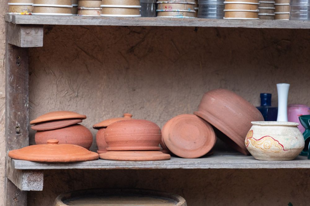 Handmade terracotta pottery on a wooden shelf