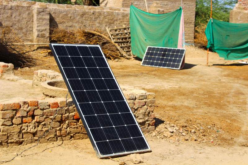 A solar panel leaning against a mud-brick wall in a compound