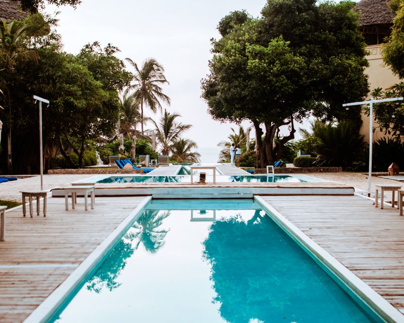 A turquoise outdoor pool among palms and timber decking
