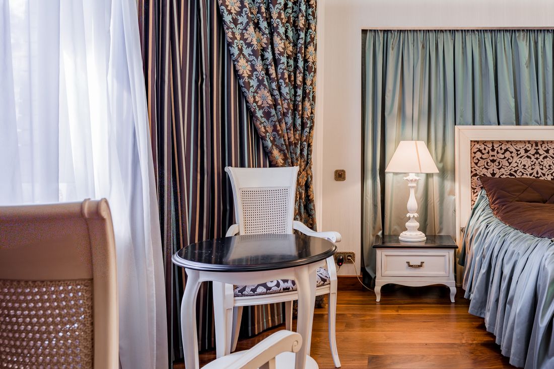 A heritage room with patterned curtains, writing desk and lamp