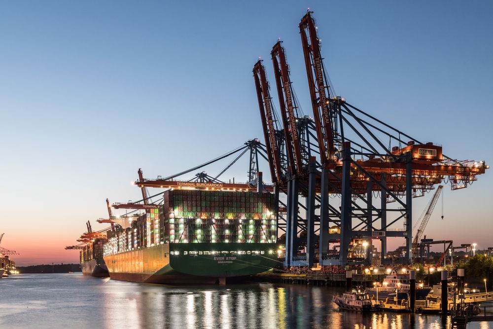 A container ship docked at a busy port at twilight