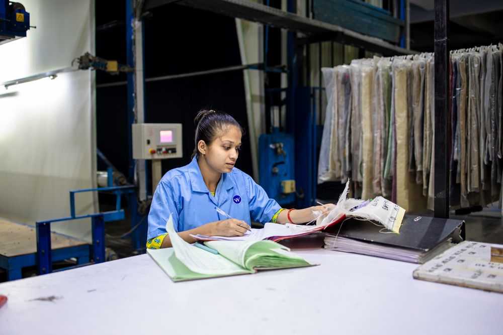 A textile worker reviewing sourcing documents at a factory