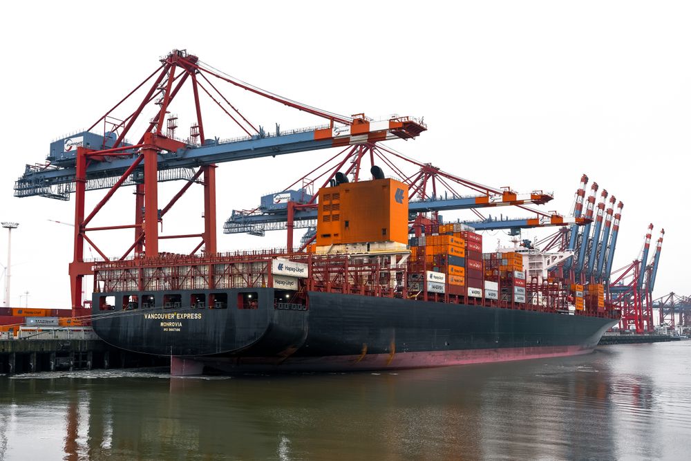 Cranes loading containers onto a vessel at a busy harbour