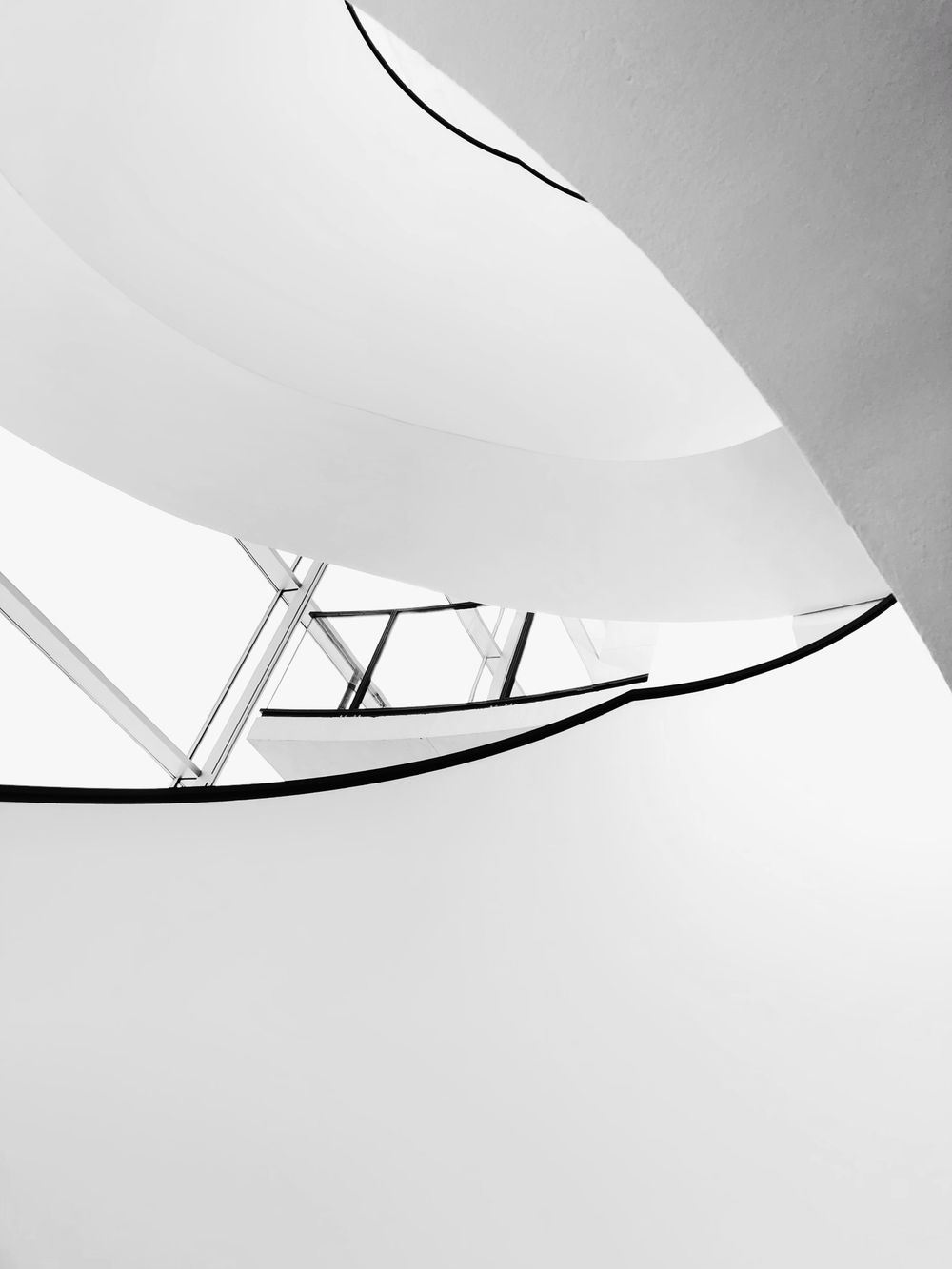 A white spiral staircase seen from below in black and white